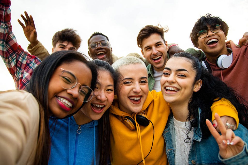 Group of multiracial teen college friends having fun outdoors.